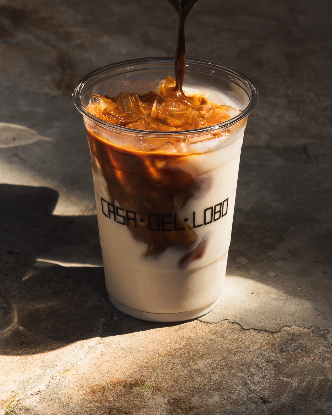 Iced latte being poured into a Casa Del Lobo cup